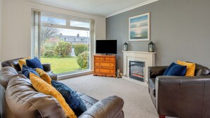 A living room with a fireplace, leather sofas, and a television. - 3 bedroom accommodation in Lamlash (Lamlash)