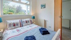 A bedroom with a bed, a window, a radiator, and a door. - 3 bedroom accommodation in Lamlash (Lamlash)