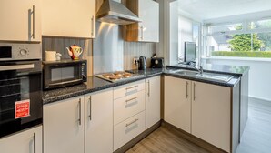 A modern kitchen with a microwave, oven, and toaster. There is a window providing a view of the outside. - 3 bedroom accommodation in Lamlash (Lamlash)