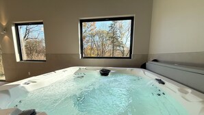 Un jacuzzi con vista a árboles a través de dos ventanas.