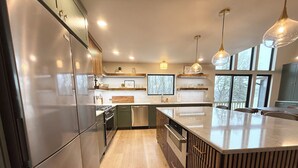 Una cocina moderna con electrodomésticos de acero inoxidable, una isla central e iluminación colgante.