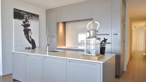 A modern kitchen with a central island, stainless steel appliances, and a decorative lantern. - Apartment in Duinbergen by the Seafront (Knokke-Heist)