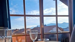 Une table à manger offrant une vue dégagée sur le ciel et les bâtiments lointains grâce à de grandes fenêtres.