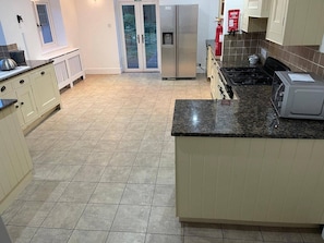 A kitchen with a refrigerator, stove, microwave, and a fire extinguisher.