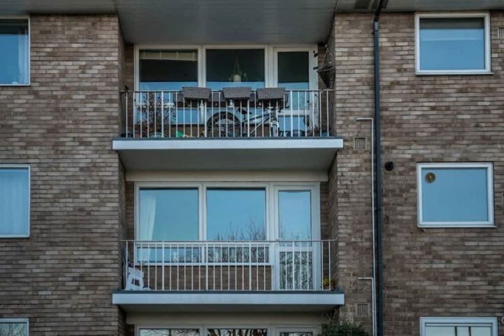 Ein zweistöckiges Gebäude mit einem Balkon im oberen Stockwerk, der einen Tisch und Stühle bietet.
