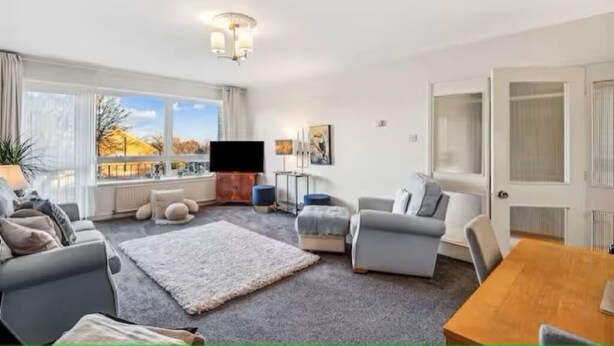 A modern living room with a sofa, armchairs, a coffee table, and a TV. - 2-Bed spacious Flat-2 minute walk from tube station direct to Central London (London)