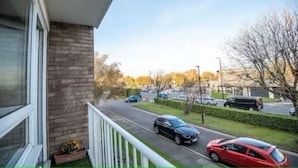 A residential street with parked cars and a house with a balcony. - 2-Bed spacious Flat-2 minute walk from tube station direct to Central London (London)