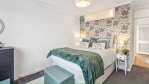 A bedroom with a bed, bedside table, lamp, and a dresser. - 2-Bed spacious Flat-2 minute walk from tube station direct to Central London (London)