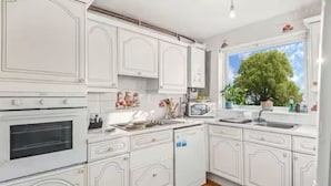 A modern kitchen with white cabinetry, a built-in oven, microwave, and sink. - 2-Bed spacious Flat-2 minute walk from tube station direct to Central London (London)