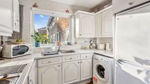 A compact kitchen with white cabinetry, a built-in washing machine, and a refrigerator. - 2-Bed spacious Flat-2 minute walk from tube station direct to Central London (London)