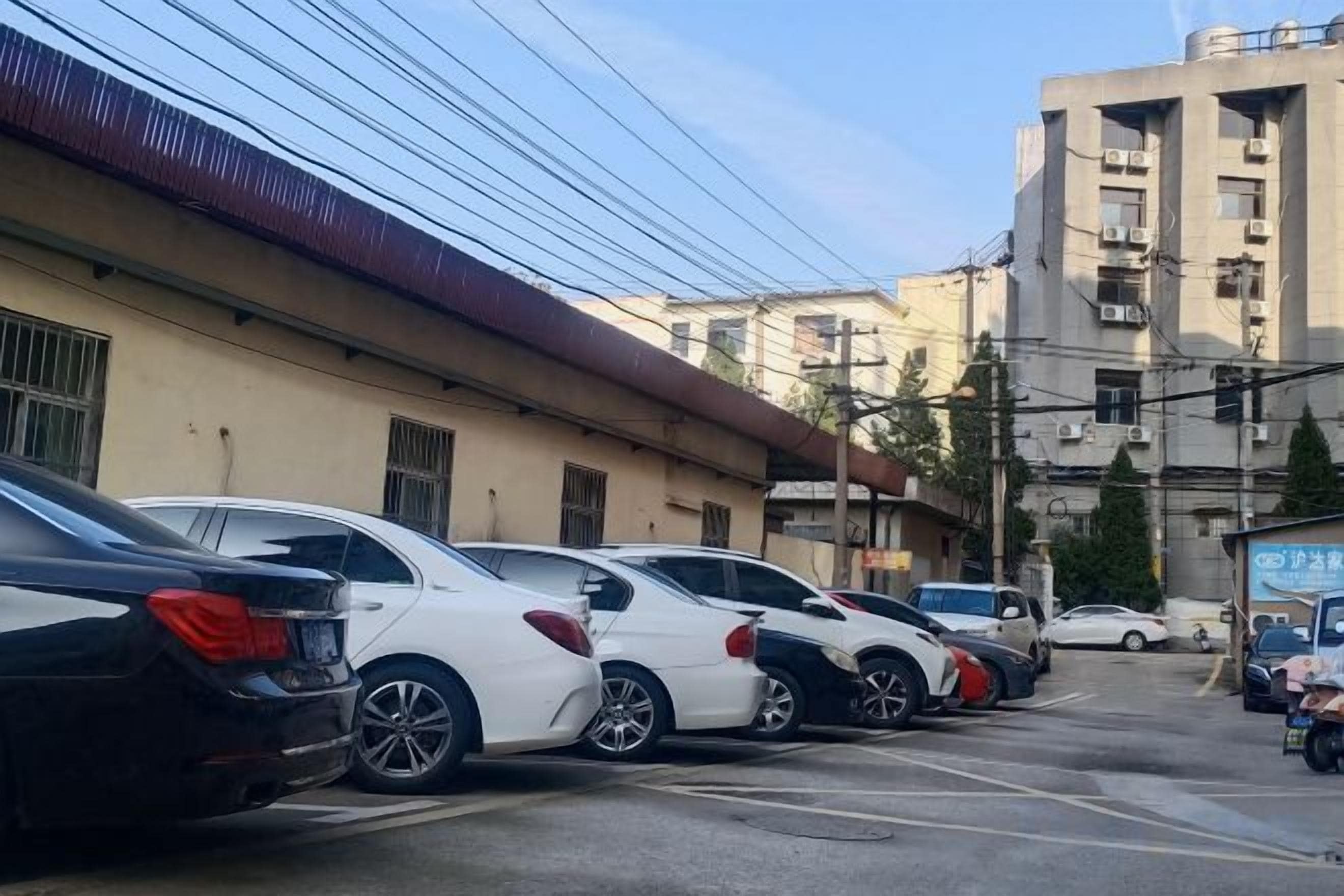 A row of parked cars in a parking lot with buildings in the background.