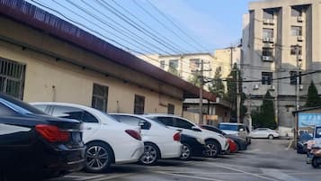 A row of parked cars in a parking lot with buildings in the background.