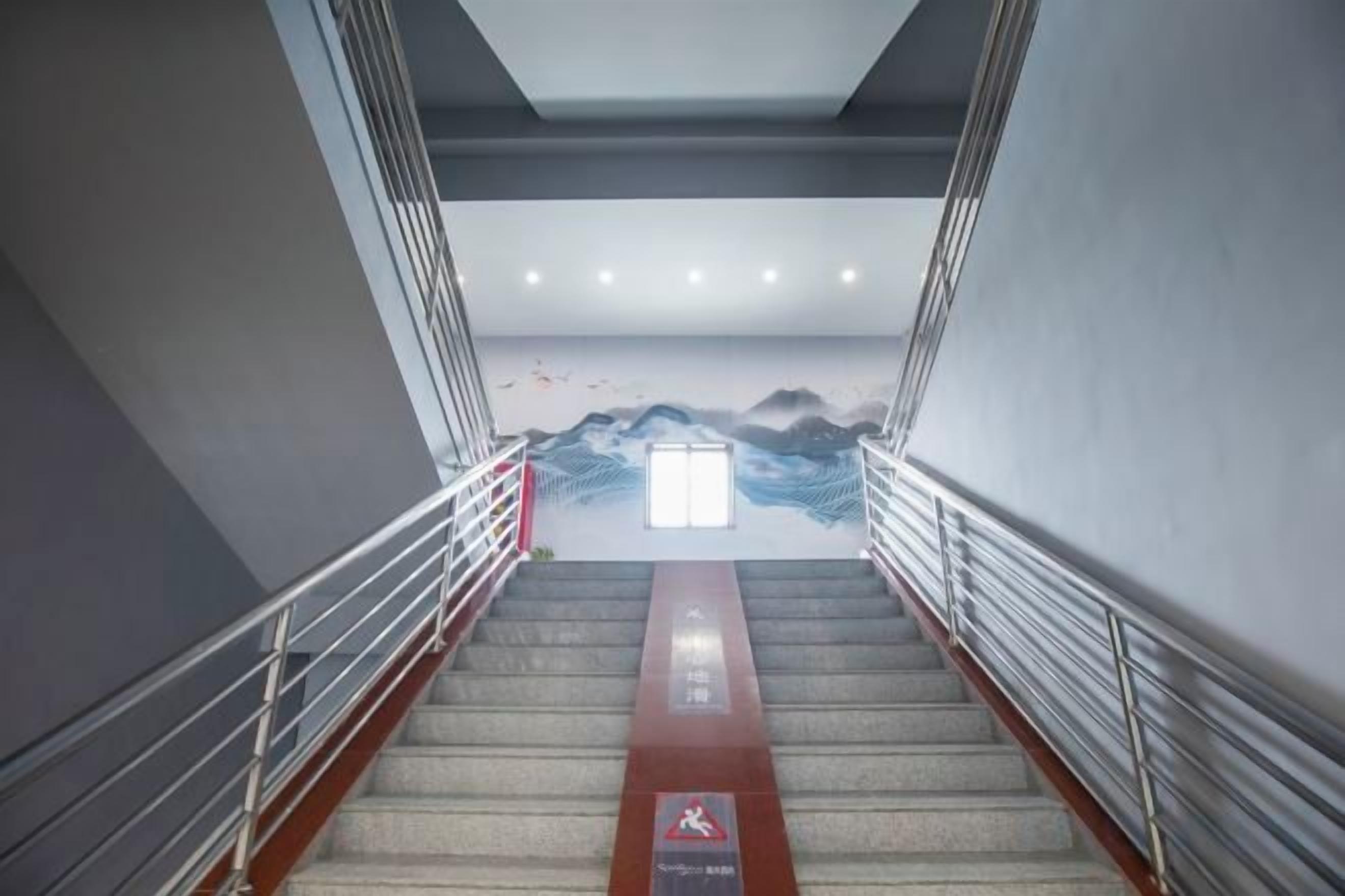 A staircase with metal railings, a red safety sign, and a wall mural.