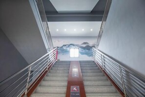 A staircase with metal railings, a red safety sign, and a wall mural. - Qingmu Hotel(Shangyuan Street,Dongshan Subway Station,Nanjing) (Nanjing)
