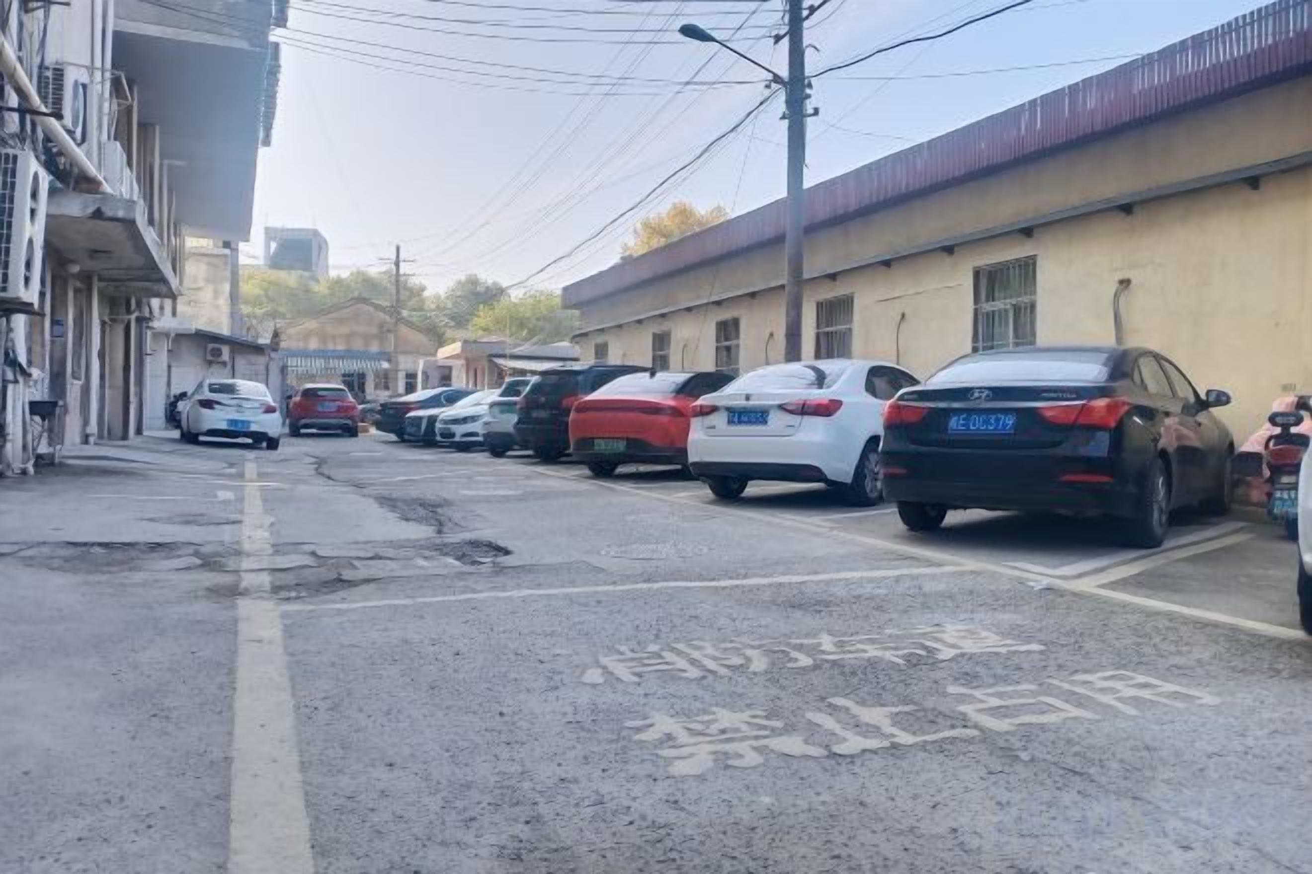 Un carrer amb cotxes estacionats i edificis.