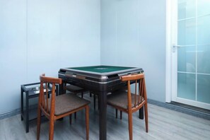 Een biljart tafel met vier stoelen in een hoekzaal, met lichtgekleurde muren en een schuifdeur van glas.