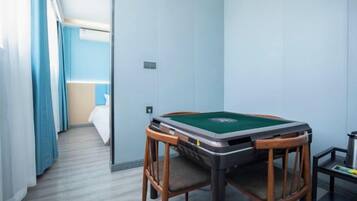 A room with a pool table, a bed, and a window with curtains.