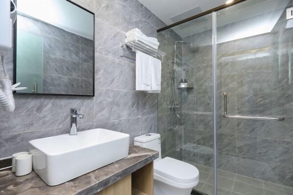 A modern bathroom with a rectangular sink, a toilet, and a glass-enclosed shower. - Qingmu Hotel(Shangyuan Street,Dongshan Subway Station,Nanjing) (Nanjing)