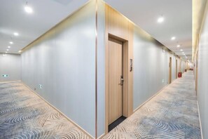 A hotel corridor with a patterned carpet, wooden doors, and recessed lighting. - Qingmu Hotel(Shangyuan Street,Dongshan Subway Station,Nanjing) (Nanjing)