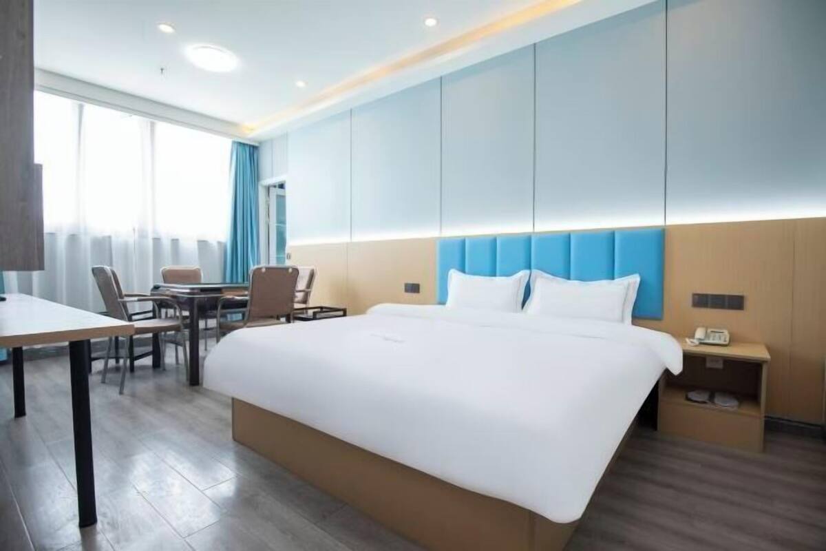 A hotel room with a large bed, a desk, and a chair.