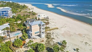 A beachfront property with a pool, multiple buildings, and a beach view.