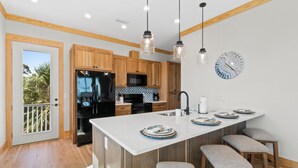 A modern kitchen with wooden cabinets, a central island with bar stools, and pendant lighting.