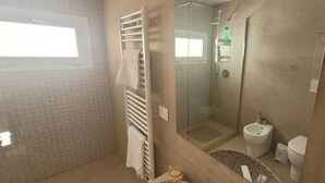 Ein Badezimmer mit Dusche, Toilette, Bidet und Handtuchhalter.