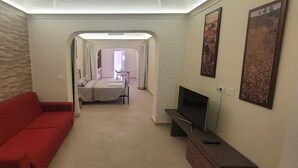 Ein modernes Wohnzimmer mit einem roten Sofa, einem Flachbildfernseher und Kunstwerken an den Wänden.