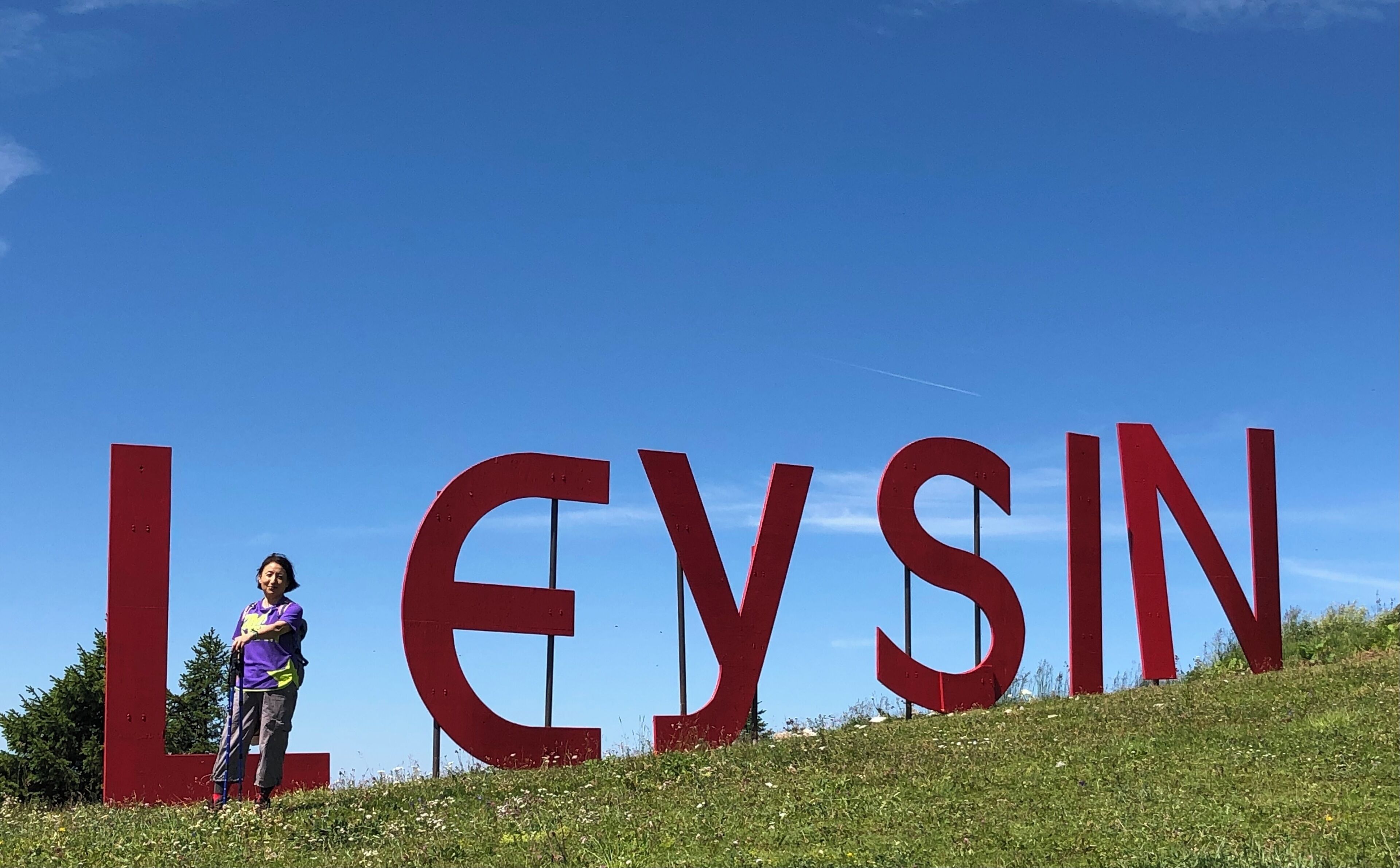A person standing in front of large red letters spelling "LEYSIN".
