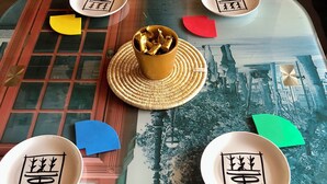 Una mesa con cubierta de vidrio decorativo, rodeada de sillas rojas.