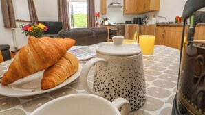 En frukostuppsättning med croissanter, en kaffekanna och ett glas apelsinjuice på ett bord.