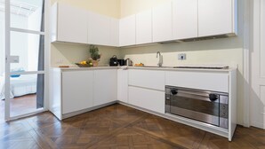 Una cocina moderna con armarios blancos, un horno de acero inoxidable y un ventanal que proporciona luz natural.