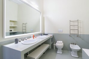 A modern bathroom with two sinks, a toilet, and a bidet.