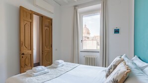 Un dormitorio con una cama, un ventanal con vistas a un edificio y un radiador.