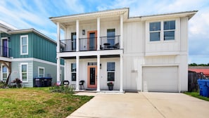 Un edificio residencial de dos pisos con porche delantero, garaje y un número de casa visible.