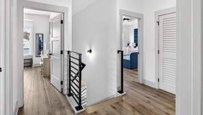 Un interior moderno con piso de madera, paredes blancas y una escalera con barandillas negras.