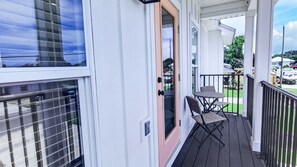 Un espacio al aire libre techado con una mesa y sillas, una puerta y vistas del entorno.