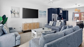 A modern living room with grey sofas, a coffee table, and a flat-screen TV.