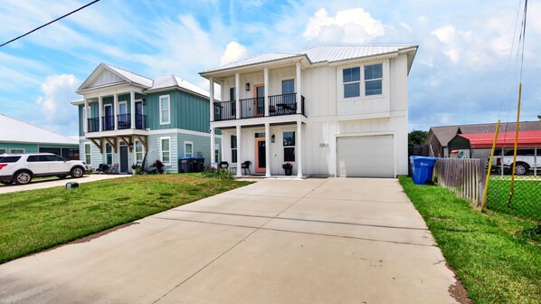 A two-story residential building with a front porch, a garage, and a well-maintained lawn.