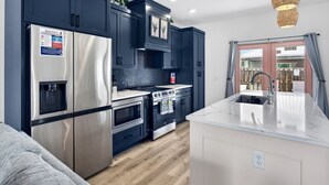 Una cocina moderna con electrodomésticos de acero inoxidable, armarios oscuros y una isla grande con un lavamanos.