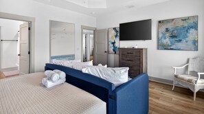 A bedroom with a bed, a dresser, a chair, and artwork on the walls.