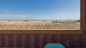 Une vue depuis un balcon donnant sur un paysage désertique, avec une végétation clairsemée et des bâtiments situés au loin.