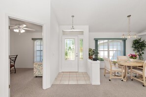 Un espace repas comprenant une table, des chaises, un ventilateur de plafond et une plante en pot.