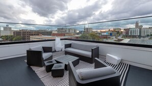 En modern takterrass med en grå soffa, två fåtöljer och ett soffbord.
