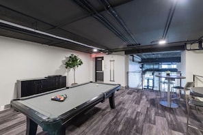 A pool table with balls, a potted plant, and a view of the outside.