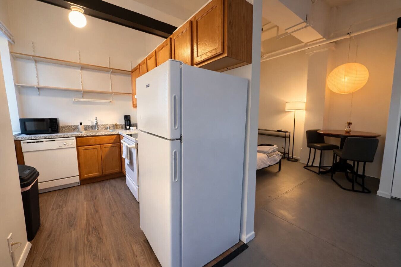 Eine kleine Küche mit Holzausstattung, einem weißen Kühlschrank, einer Mikrowelle und einem Geschirrspüler.