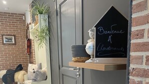 Un interior moderno con una puerta gris, una repisa con objetos decorativos y una pared de ladrillo.
