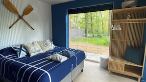 Un dormitorio con cama, un armario de madera y una ventana que ofrece vistas a la vegetación.