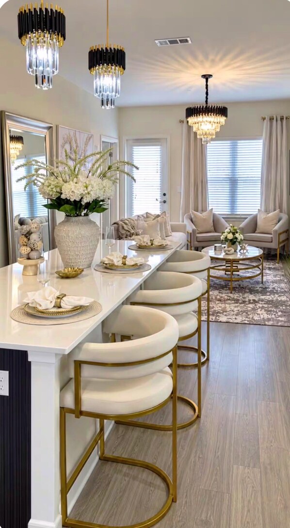A modern kitchen with a long island, bar stools, and pendant lighting.