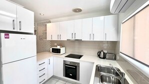 A compact kitchen with white cabinets, a built-in microwave, a stove, an oven, and a sink.